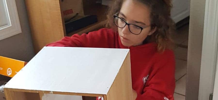 Hailey Noether helps paint shelves at the new Quinton's House