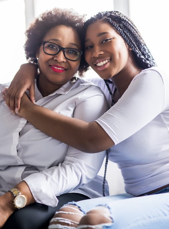 Mother and daughter sitting together on sofa