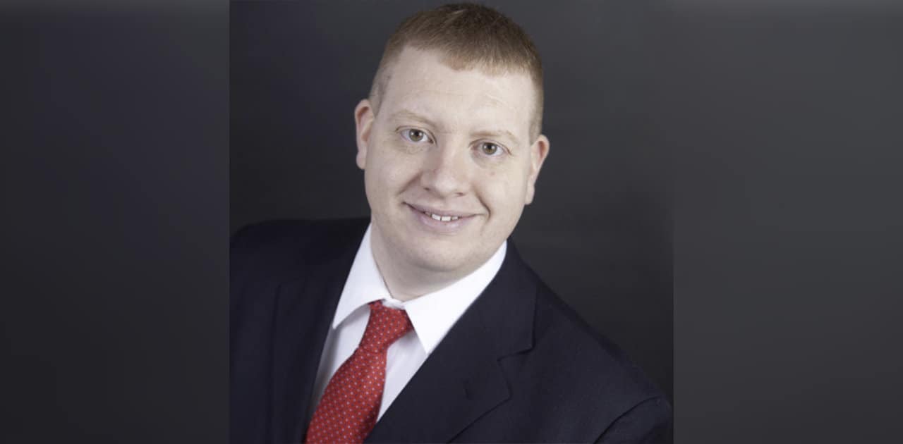 Studio portrait of Jeff Knoop in a suit on a dark background