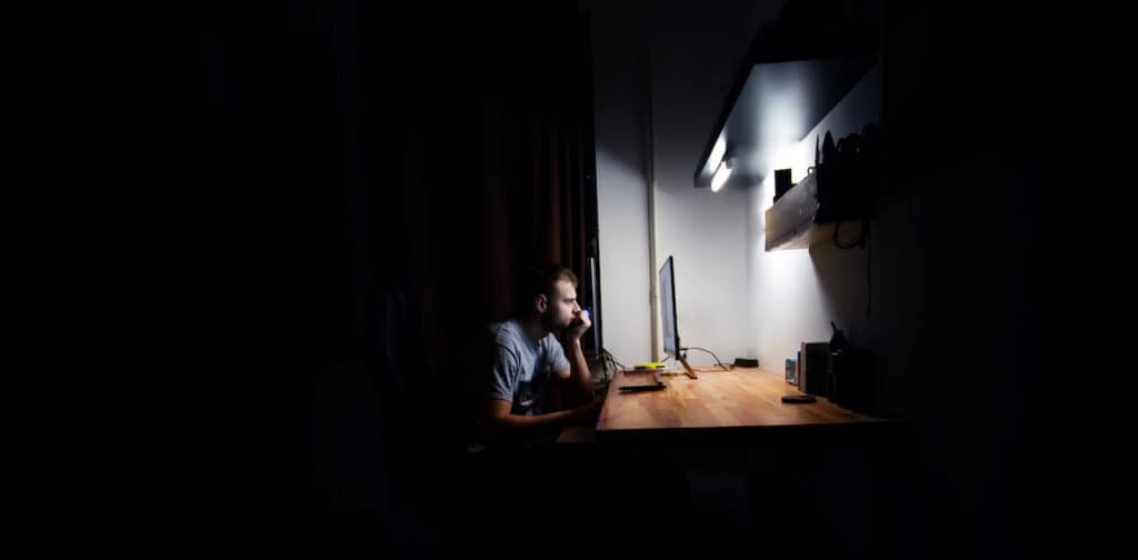 Man working at his computer in a dark room late at night
