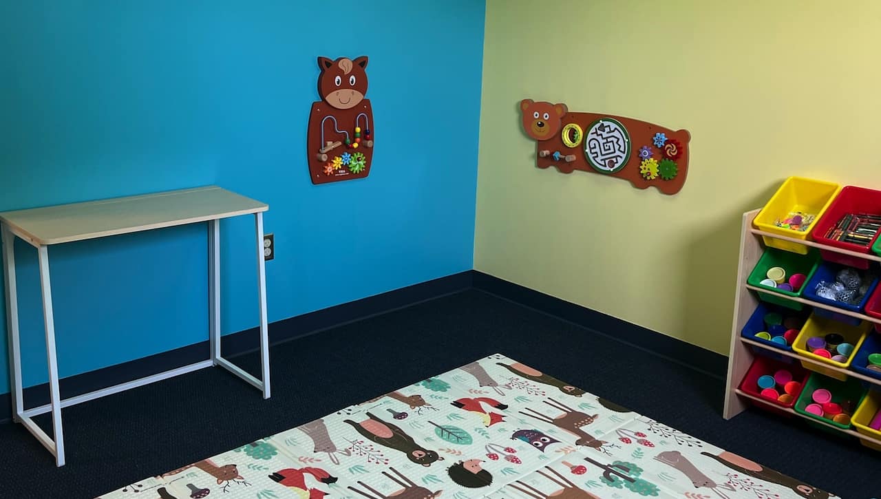 A table, puzzle, mat, and shelf sit against blue and yellow walls at The CASIE Center