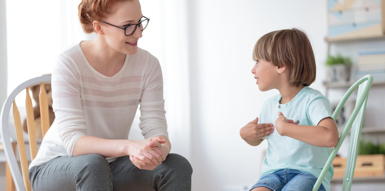 A young boy talks with an adult woman in a small room.